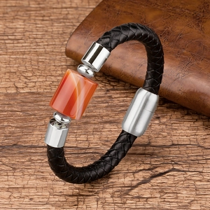 Detail view of woven black leather bracelet with orange tiger eye stone and silver clasp