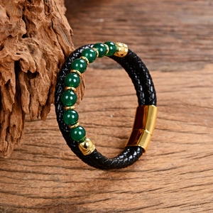 Detail of double-layer black leather bracelet with green stone beads and golden clasp