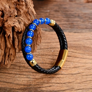 Black braided leather bracelet with blue stone beads and golden magnetic clasp on wood