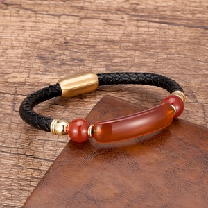 Detail of black braided leather bracelet with orange stone inlay and gold magnetic clasp