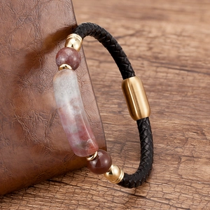 Close-up of woven black leather bracelet with red stone bead and gold magnetic clasp