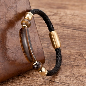 Detailed macro view of woven black leather bracelet with tiger eye stones and gold buckle