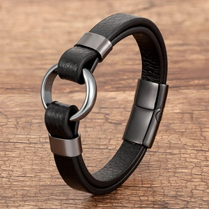 Detailed close-up of a black braided leather bracelet with magnetic metal clasp on wood