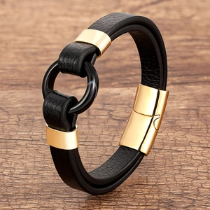 Detail of black leather braided bracelet with gold magnetic clasp on wooden background