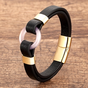 Detail of black leather braided bracelet with gold magnetic clasp and purple ring