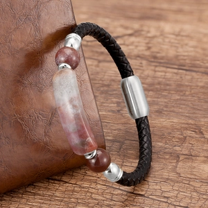 Macro detail of men's braided leather bracelet with red stone beads and magnetic clasp