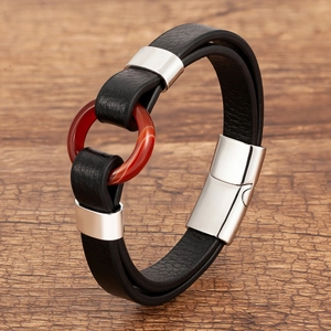 Detail of black woven leather bracelet with red agate ring and magnetic metal clasp