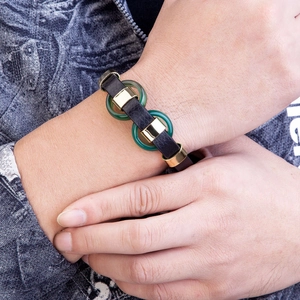 Bracelet classique en cuir tressé avec fermoir doré et pierres vertes porté au poignet