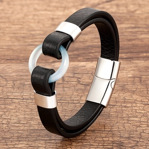 Detail of black braided leather bracelet with silver magnetic clasp and jade-like ring