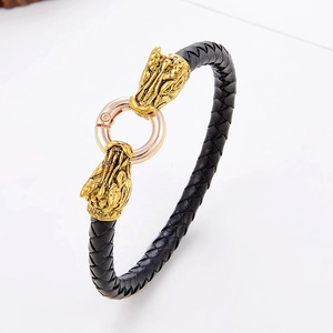 Dettaglio del bracciale in pelle intrecciata nera con teste di drago dorate e chiusura