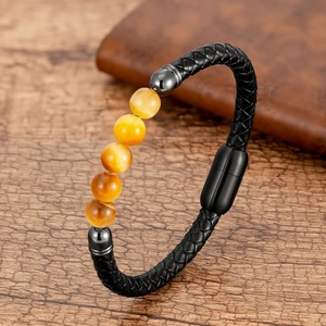 Detalle de pulsera de cuero trenzado negro con cuentas de ojo de tigre amarillas