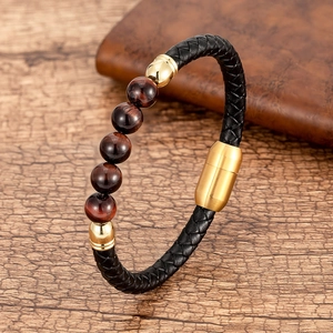 Detalle de pulsera de cuero trenzado negro con cuentas ojo de tigre y cierre dorado imán