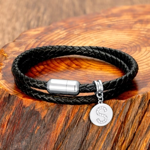 Close-up of black braided leather double-layer bracelet with silver 'S' letter pendant