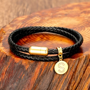 Close-up of double-layered black braided leather bracelet with golden diamond S pendant
