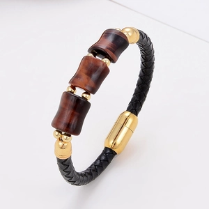 Detail eines schwarzen Lederarmbands mit braunen Tigerauge-Steinen und Goldverschluss