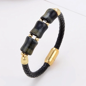 Nahaufnahme von geflochtenem Lederarmband mit Tigeraugen-Steinen und Gold-Magnetverschluss