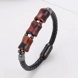 Detail eines geflochtenen schwarzen Lederarmbandes mit Tigerauge-Steinen und Magnetverschluss