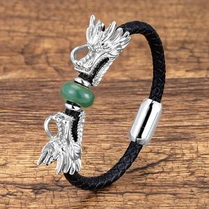 Macro shot of silver dragon head bracelet with green bead and black braided leather
