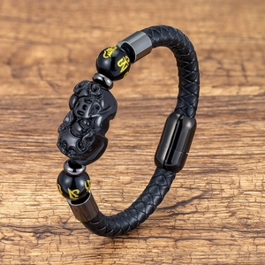 Detail of woven leather bracelet with PiXiu charm and magnetic clasp on wooden base