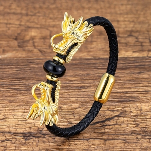 Close-up of golden dragon heads and black stone on braided leather bracelet for men