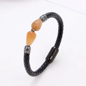 Detail of woven black leather bracelet featuring amber beads and black magnetic metal clasp