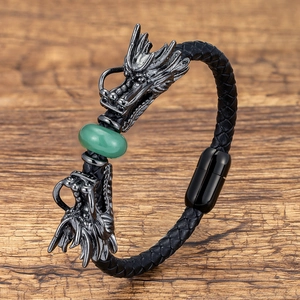 Detailed macro view of metal dragon heads with green stone bead on braided leather bracelet