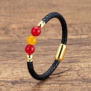 Detail of woven black leather bracelet with red and orange beads and gold magnetic clasp