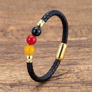Detail of woven leather bracelet with magnetic clasp and tricolor beads on wood