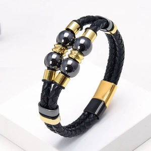 Detail of double-layer black braided leather bracelet with golden clasp and beads