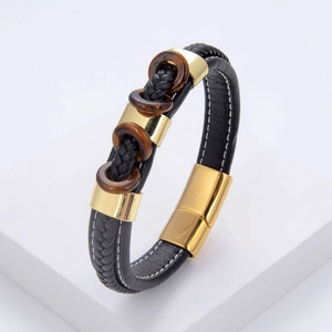 Détail d'un bracelet pour homme en cuir tressé avec fermoir doré et pierres d'œil de tigre