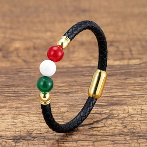 Detail of black braided leather bracelet featuring polished red white and green beads