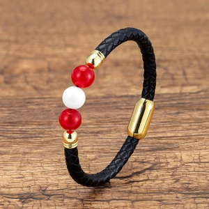 Close-up of woven leather bracelet featuring vibrant red beads and a gold magnetic clasp