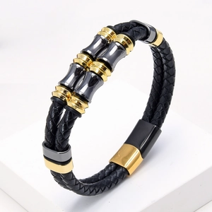 Detailopname van gevlochten zwart leren armband met goud- en gunmetal-kleurige accenten