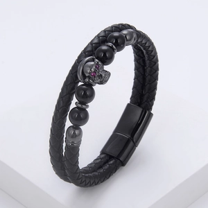Macro detail of men's double-layer braided leather bracelet with skull charm and magnetic clasp