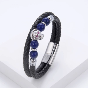 Detail of double-layer black leather bracelet with blue stones and skull charm