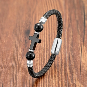 Détail d'un bracelet en cuir tressé noir avec pendentif croix et fermoir magnétique argenté