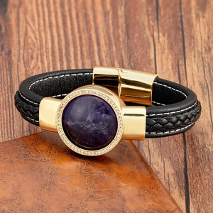 Dettaglio di bracciale in pelle nera intrecciata con grande pietra viola e chiusura d'oro