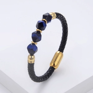 Detailansicht aus schwarzem geflochtenem Leder mit blauen Steinen und goldenem Metallverschluss