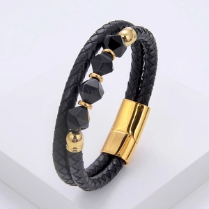 Close-up of black braided leather bracelet featuring geometric beads and gold magnetic clasp