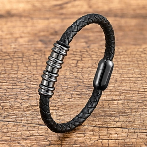 Dettaglio del bracciale in pelle nera intrecciata con anelli metallici su base in legno