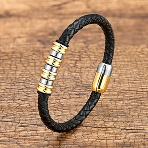 Bracciale in pelle intrecciata con anelli d'acciaio bicolore su fondo in legno