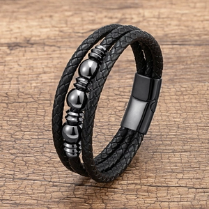 Détail d'un bracelet multicouche en cuir tressé noir avec perles en métal gris