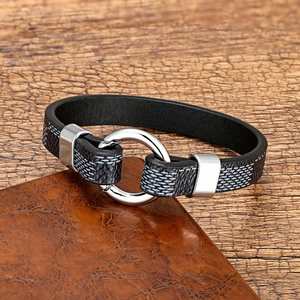 Close-up of leather bracelet with polished silver metal ring on brown background
