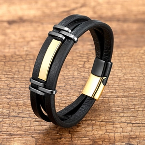 Detail van meerlaagse zwarte leren armband met gouden accenten en magnetische sluiting