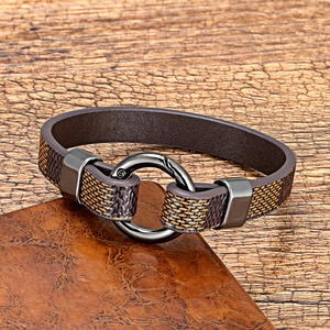 Deep brown leather and fabric braided bracelet with round gunmetal clasp on wooden desk