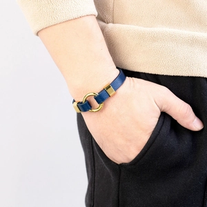 Men's navy blue leather bracelet with gold metal clasp on a male model's wrist