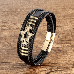 Detail view of multi-layer black leather bracelet with golden star charm and magnetic clasp
