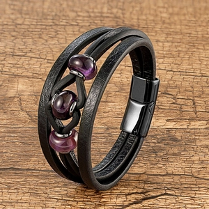 Gros plan d'un bracelet en cuir noir multicouche avec perles violettes et fermoir aimanté