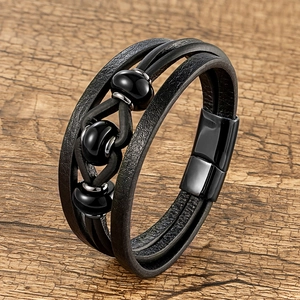 Gros plan d'un bracelet multicouche en cuir noir avec perles sombres sur bois