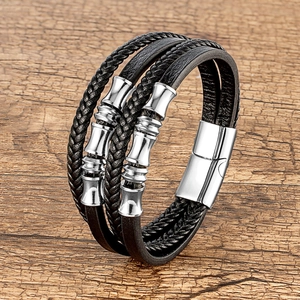 Detail van meerlaagse gevlochten lederen armband met bamboe bedeltjes en magneetsluiting